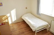 kleinere slaapkamer met wastafel, 1-persoonsbed en kinderbedje.